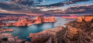 🌊 Lake Powell (Page, Arizona) Waterfront RV Camping 1 Panoramic view of Lake Powell with calm blue waters surrounded by towering red rock canyon walls under a clear sky.