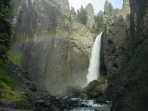 Tower Fall – Yellowstone’s Classic Waterfall 4 Tower Fall waterfall at ground level with surrounding forest and a rainbow arching over the scene.
