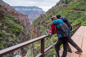 Exploring Flagstaff, Arizona: Gateway to the Grand Canyon and Northern Northern Arizona 4 Two hikers with backpacks lean on a bridge railing, gazing into a vast mountain valley filled with soft light and mist — a peaceful moment of reflection and exploration.