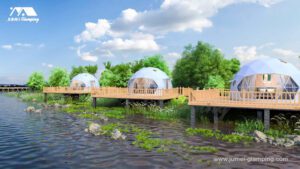 Glamping domes on wooden platforms with decks and railings along a scenic river.