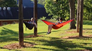 🏕️ Glamping Comfort & Relaxation: 50 Products for A Cozy Outdoor Experience 5 Two people relaxing in hammocks outdoors, enjoying a peaceful moment.