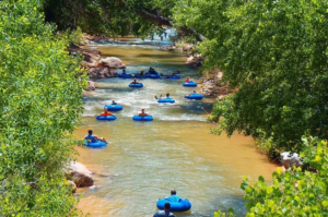 Visitors enjoy a relaxing tubing adventure on the Virgin River near Zion National Park, floating through calm waters surrounded by lush green trees and beautiful canyon scenery in southwestern Utah.