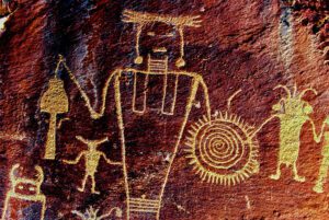 Red rock featuring intricate carvings and designs in a natural outdoor setting.