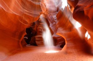 Sunlight streaming through the narrow walkway of Antelope Canyon, illuminating the sandstone walls.