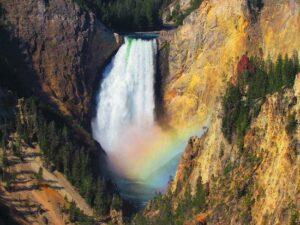 Waterfalls seen from a distance with a rainbow arching over the scene.