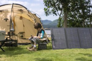 Person sitting at a campsite with solar panels, generator, and a luxury glamping tent.