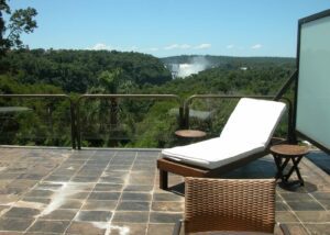 Gran Meliá Iguazú (Argentina) – Luxury With A Front-Row View of Iguazú Falls 🌊✨ 5 Balcony with chair and lounge chair overlooking rainforest with Iguazú Falls visible in the distance.