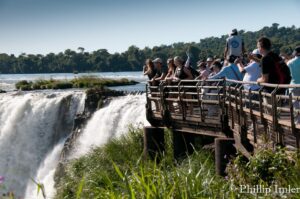 Several people standing on a walkway overlooking Iguazú Falls.