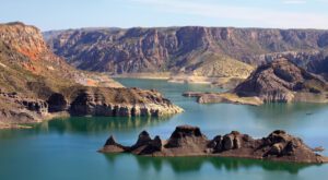 Lake nestled in a valley with steep canyon walls at Cañón del Atuel, Argentina, surrounded by rugged mountains and natural scenery.