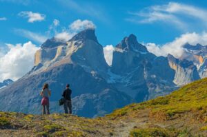 Two hikers walking across flat terrain with mountains in the background under a clear sky.