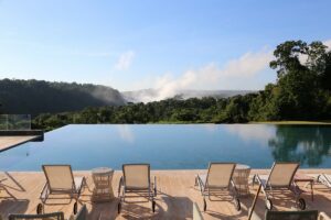 Gran Meliá Iguazú (Argentina) – Luxury With A Front-Row View of Iguazú Falls 🌊✨ 3 Swimming pool with lounge chairs, surrounded by rainforest, with Iguazú Falls visible in the distance.