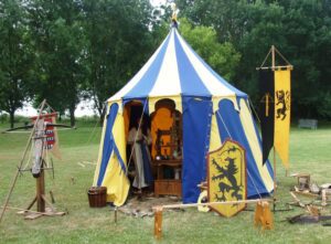 🌞🌈🏔️🌿Unique & Novelty Tents: 30 Medieval, Tipi & Yurts for Glamping & Festivals🎪🔥 2 Medieval blue and yellow tent with trees in the background