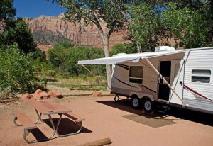 White RV parked at a campsite in a canyon surrounded by trees