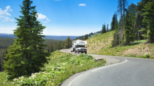RV traveling along a scenic mountain road in Yellowstone National Park surrounded by evergreen forests, rolling hills, and breathtaking wilderness.