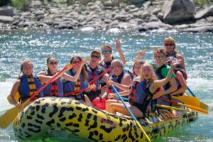 Raft with several people navigating a river in Yellowstone National Park surrounded by natural landscape and scenic outdoor environment