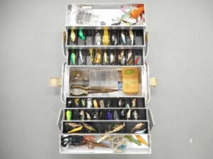 Multi-tier fishing tackle box organized with fishing lures, crankbaits, spinnerbaits, spoons, hooks, sinkers, swivels, bobbers, leaders, and terminal tackle for freshwater and saltwater fishing adventures.