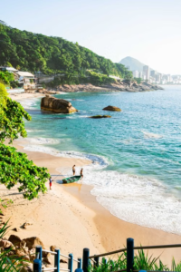 Prainha Beach in Rio de Janeiro surrounded by lush rainforest-covered mountains with turquoise Atlantic water, sandy shoreline, rocky cliffs and rolling surf.