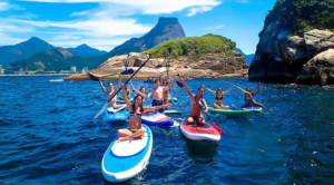 Rio’s Beaches, Coastal Trails & Outdoor Adventures 14 Group of paddleboarders exploring blue coastal waters near rocky islands and mountains in Rio de Janeiro, Brazil.