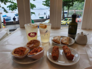🚠 Sugarloaf Mountain & Urca – Trails, Beaches & Guanabara Bay 14 Brazilian snacks and refreshing drinks served at a waterfront restaurant in Urca, Rio de Janeiro, overlooking Guanabara Bay.