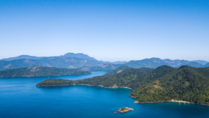 🏝️ Ilha Grande – Beaches, Rainforest Trails, Kayaking & Island Adventures 4 Panoramic view of Ilha Grande, Brazil, with blue ocean waters, forest-covered islands, secluded coves, and mountains in the distance.