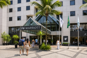 Rio’s Beaches, Coastal Trails & Outdoor Adventures 21 Daytime view of the JW Marriott hotel entrance in Rio de Janeiro with palm trees and travelers walking toward and through the entrance.