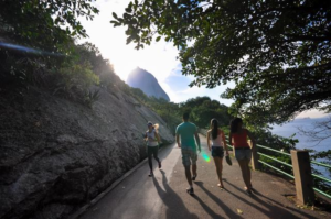 🚠 Sugarloaf Mountain & Urca – Trails, Beaches & Guanabara Bay 6 Hikers walking along a scenic trail surrounded by tropical vegetation and rocky slopes near Morro da Urca and Sugarloaf Mountain in Rio de Janeiro.