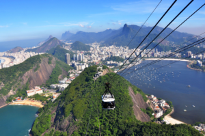 🚠 Sugarloaf Mountain & Urca – Trails, Beaches & Guanabara Bay 16 Sugarloaf cable car traveling above forested mountains with Guanabara Bay, Rio de Janeiro beaches and the city skyline in the distance.