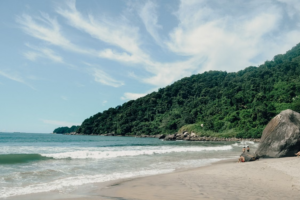 🏝️ Ilha Grande – Beaches, Rainforest Trails, Kayaking & Island Adventures 10 Quiet tropical beach on Ilha Grande, Brazil, surrounded by lush rainforest, large coastal rocks, and gentle ocean waves.