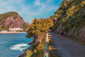 🚠 Sugarloaf Mountain & Urca – Trails, Beaches & Guanabara Bay 7 Hikers walking along the scenic Cláudio Coutinho Trail beside the ocean and tropical forest in Rio de Janeiro, Brazil.