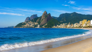 Rio de Janeiro coastline with sandy beach, Atlantic Ocean, city skyline and forest-covered mountains.