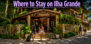 Travelers walking toward the entrance of a tropical hotel on Ilha Grande, Brazil, surrounded by lush rainforest plants.