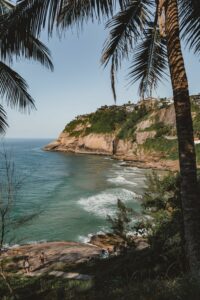 Joatinga Beach in Rio de Janeiro with turquoise Atlantic water, secluded golden sand, rocky cliffs, tropical vegetation and hillside homes overlooking the coastline.