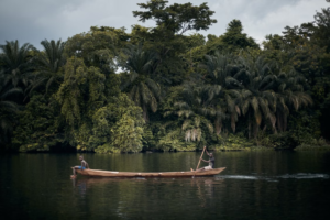 🌊 West & Central Africa River Safaris – Wildlife, Boat Adventures & Scenic Waterways 6 Traditional wooden canoe traveling along a calm tropical river surrounded by dense rainforest vegetation in Gabon.