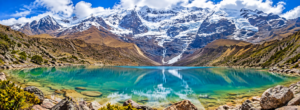 Humantay Lake & Andes Mountain Adventure Guide 1 Humantay Lake in the Peruvian Andes with turquoise water, snow-covered mountains, glaciers, and rocky shoreline.