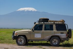 🚐 African Camper Safaris – Epic Road Trips, Wildlife & Camping Adventures 10 4×4 safari vehicle parked on the African plains with snow-capped Mount Kilimanjaro rising in the background.