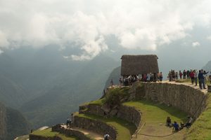 Machu Picchu & Sacred Valley Mountain Adventures: Hiking, Scenery & Outdoor Experiences 3 Hikers exploring elevated stone terraces at Machu Picchu with dramatic Andes Mountains and clouds in the background.