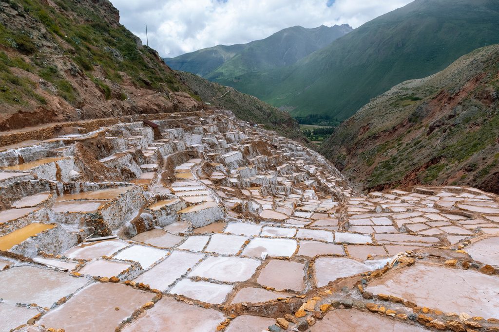 Panoramic view of the Maras Salt Mines in Peru's Sacred Valley, featuring thousands of traditional salt pools cascading down an Andean hillside.