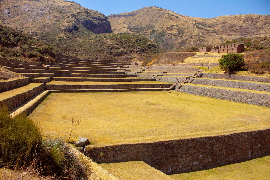 Ancient Inca agricultural terraces with stone retaining walls extending across a mountainous landscape in Peru.