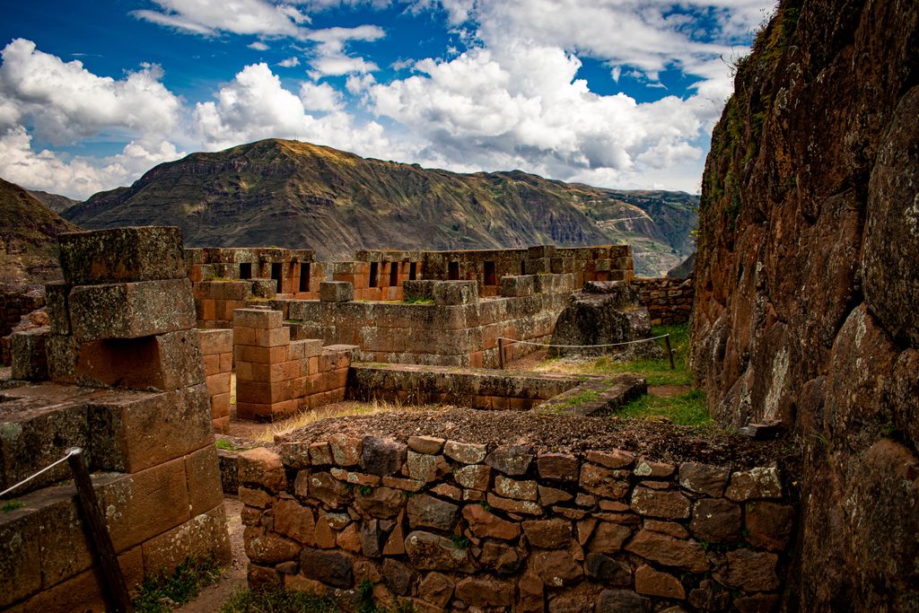 Ancient Inca stone walls and archaeological ruins surrounded by dramatic Andean mountain scenery in Peru.