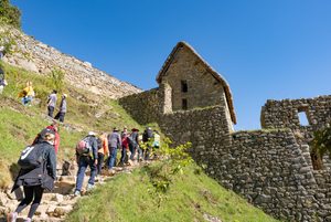 Machu Picchu & Sacred Valley Mountain Adventures: Hiking, Scenery & Outdoor Experiences 2 Hikers climbing steep stone steps through ancient Inca ruins near Huayna Picchu at Machu Picchu, Peru.